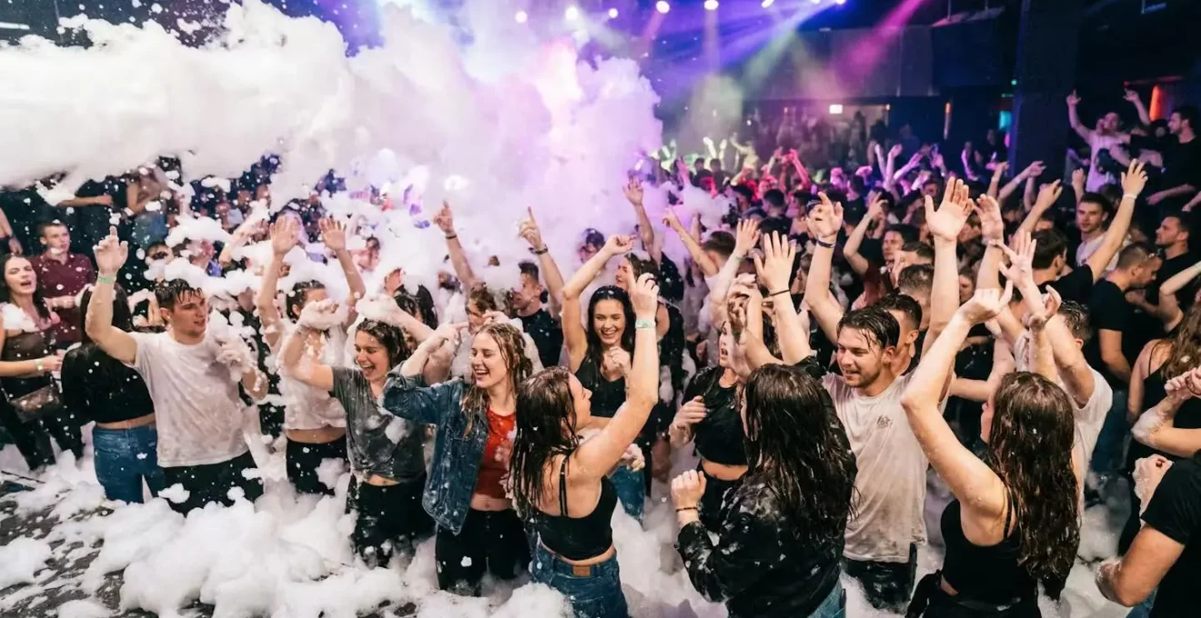 Animation mousse party avec foule dansant dans nuage de mousse blanche sous éclairage coloré